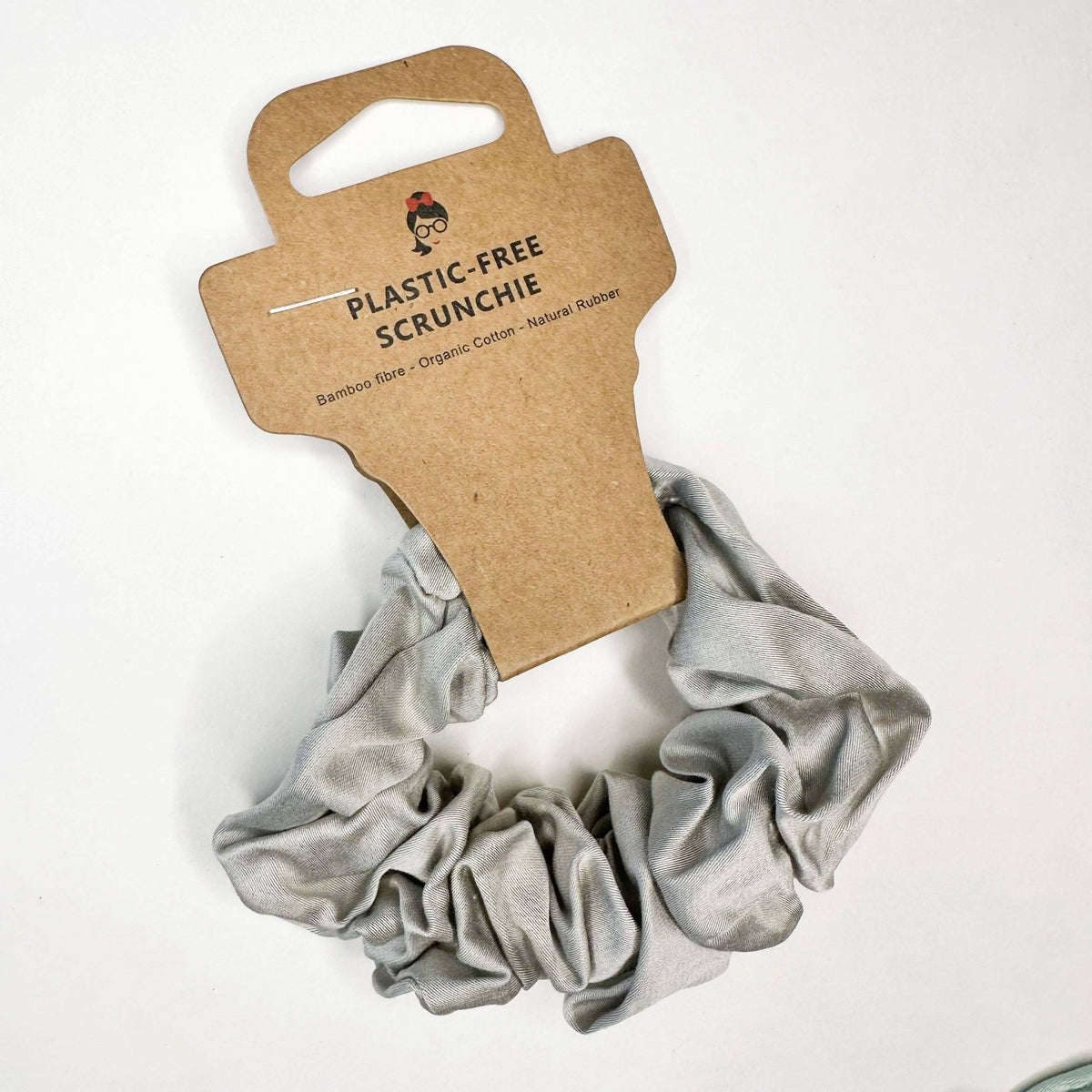 Gray scrunchie on a cardboard holder with 'Plastic-Free Scrunchie' text on a white background