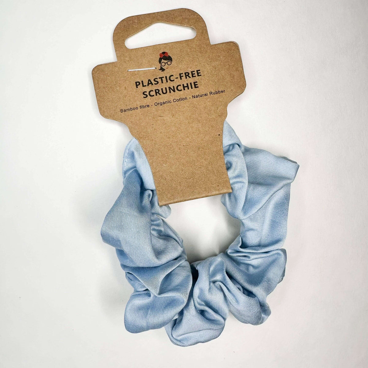 Light blue scrunchie with a cardboard packaging label on a white background