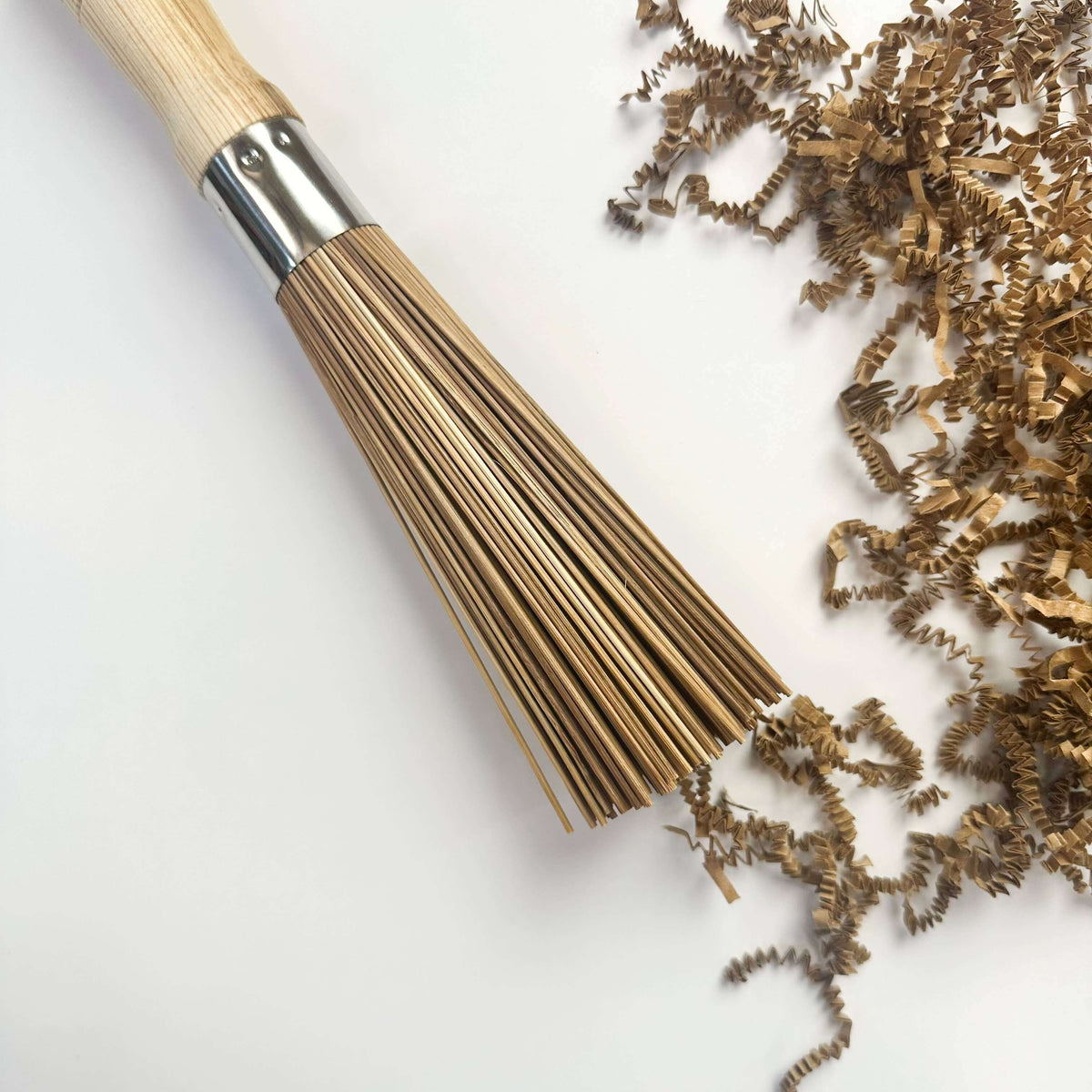 Wooden brush with bristle head and scattered bristles on a light background