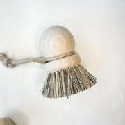 Bristle brush with a wooden handle and rope on a white background