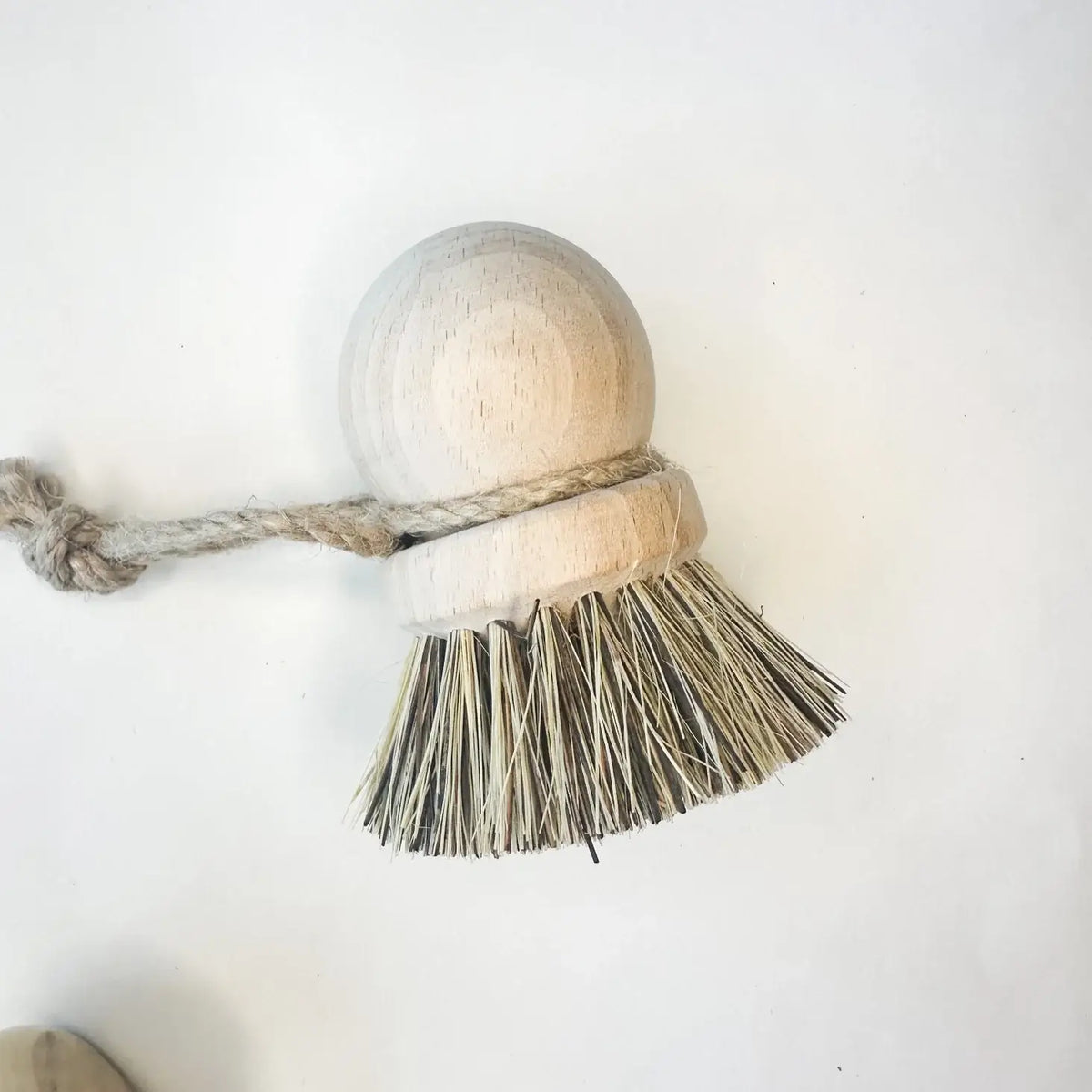 Bristle brush with a wooden handle and rope on a white background