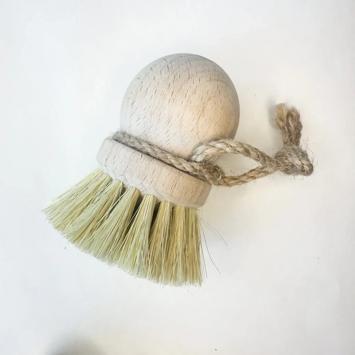 Dish brush with bristles wrapped in twine on a white background