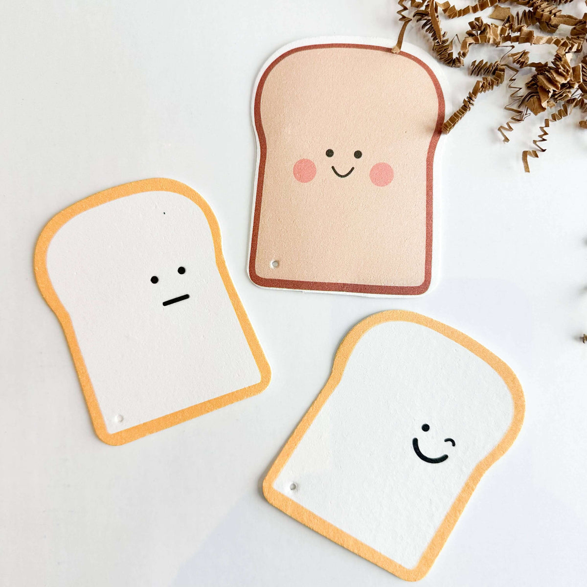 Three bread-shaped plush toys with smiling faces on a light background