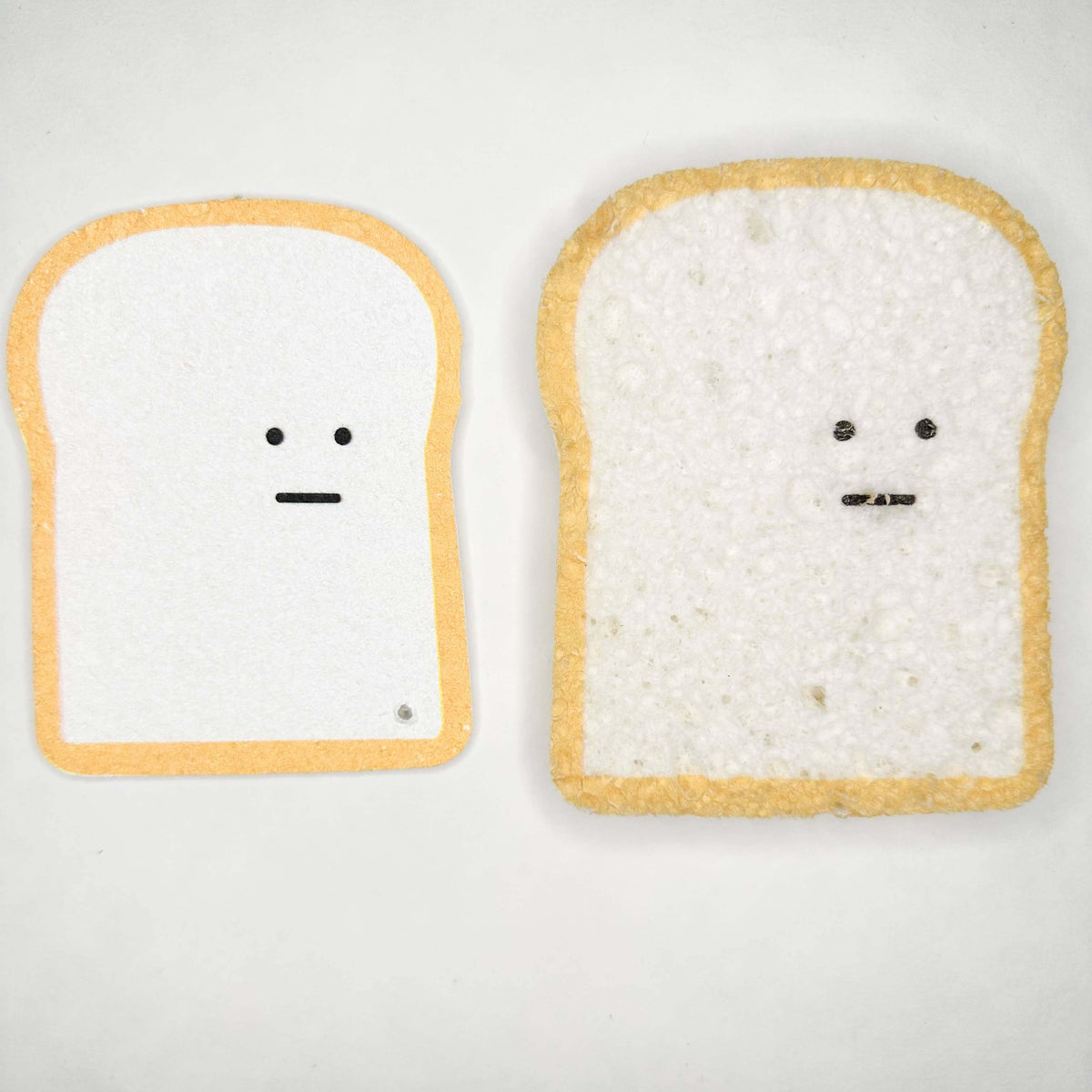 Two pieces of bread with faces drawn on a white background
