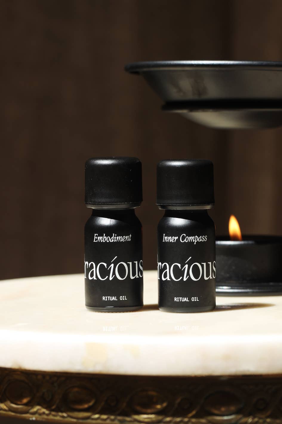 Embodiment Essential Oil Blend and Inner Compass ritual gels on a marble surface with a candle in the background.