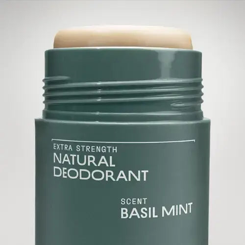 Green deodorant stick with 'Basil Mint' scent on a light gray background