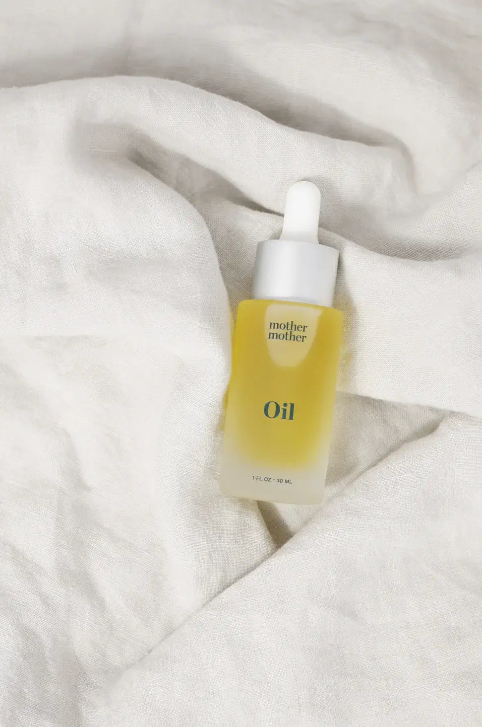 Skincare dropper bottle labeled 'Oil' on a textured white surface