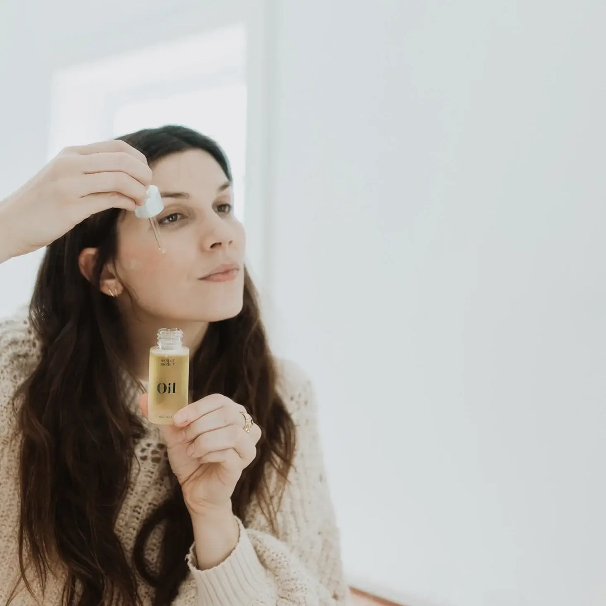 Woman applying oil to her face with a dropper bottle.