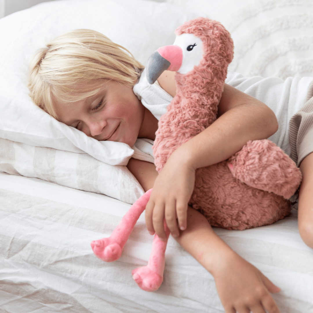 Child peacefully sleeping with Francesca The Flamingo Weighted Teddy for comfort and emotional support.