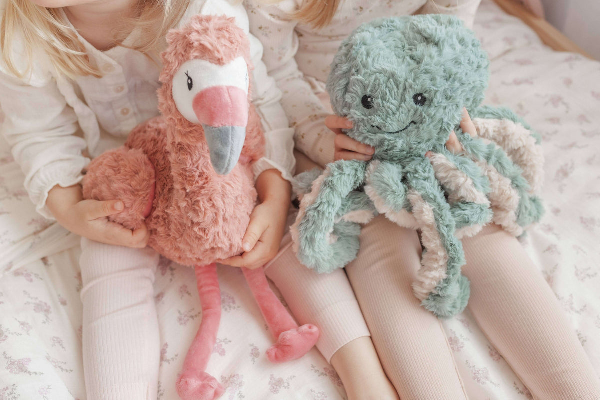Francesca The Flamingo Weighted Teddy cuddled by children, promoting comfort and support for kids.