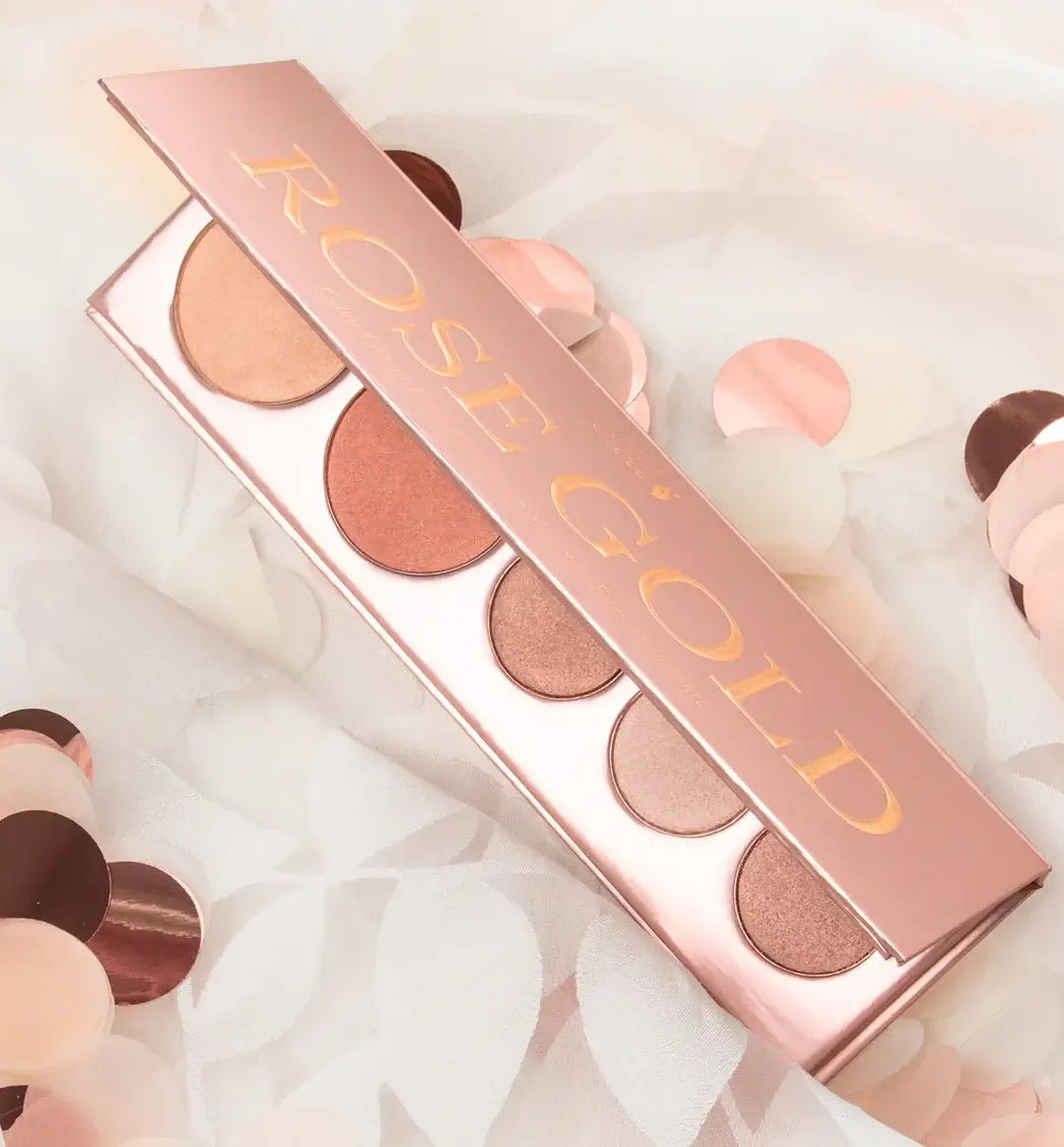 Rose gold makeup palette with round cosmetic discs on a soft white background