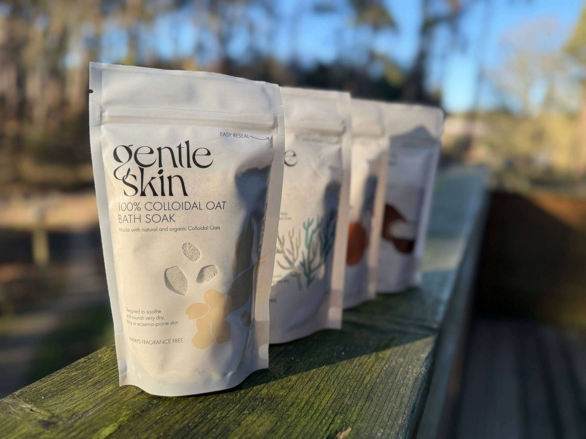 Gentle Skin bath soak packages on a wooden surface with a blurred natural background