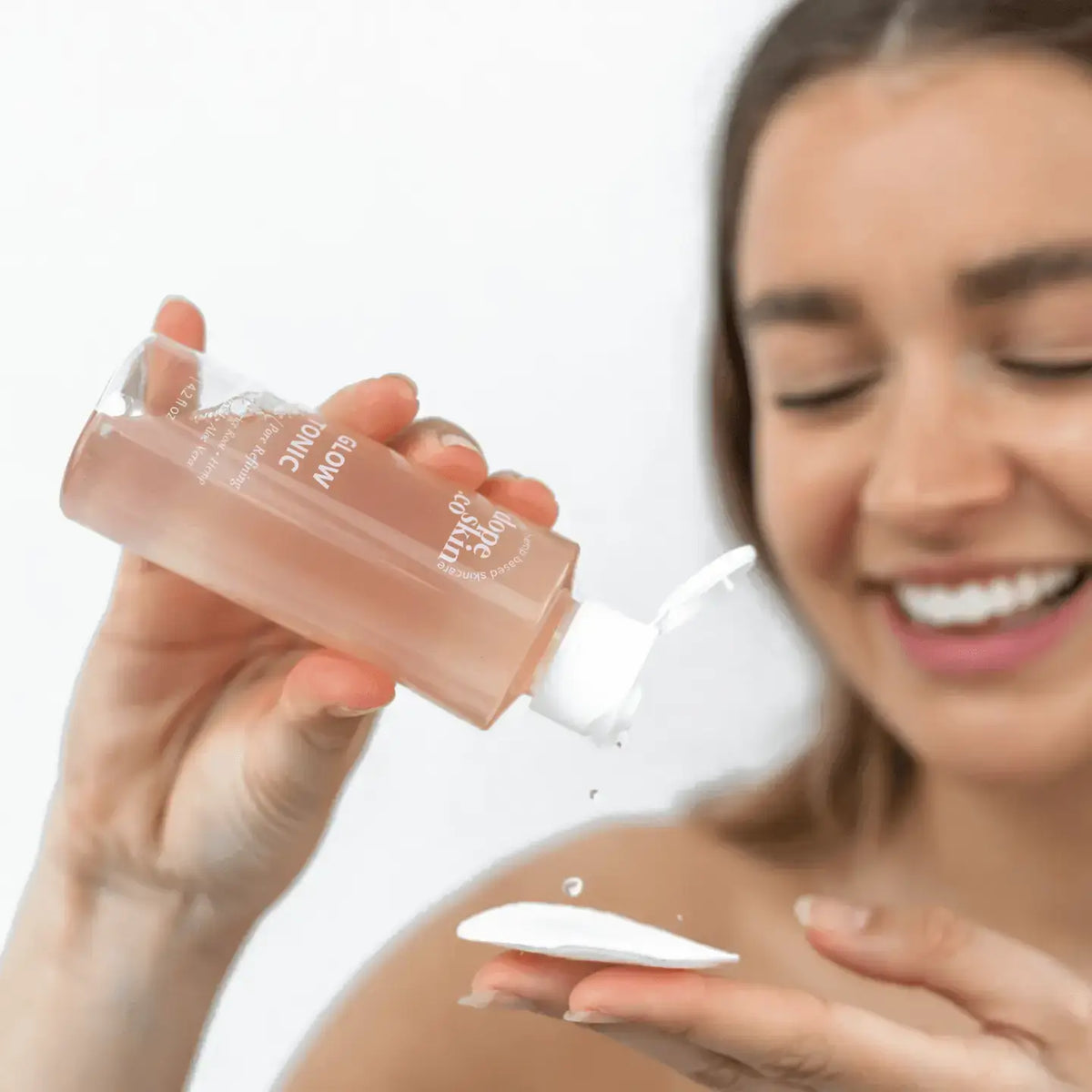 Glow Tonic being poured into a hand, showcasing its brightening properties for radiant skin.