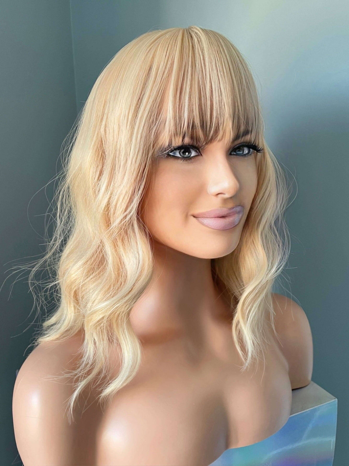 Mannequin head with a blonde wig on a gray background