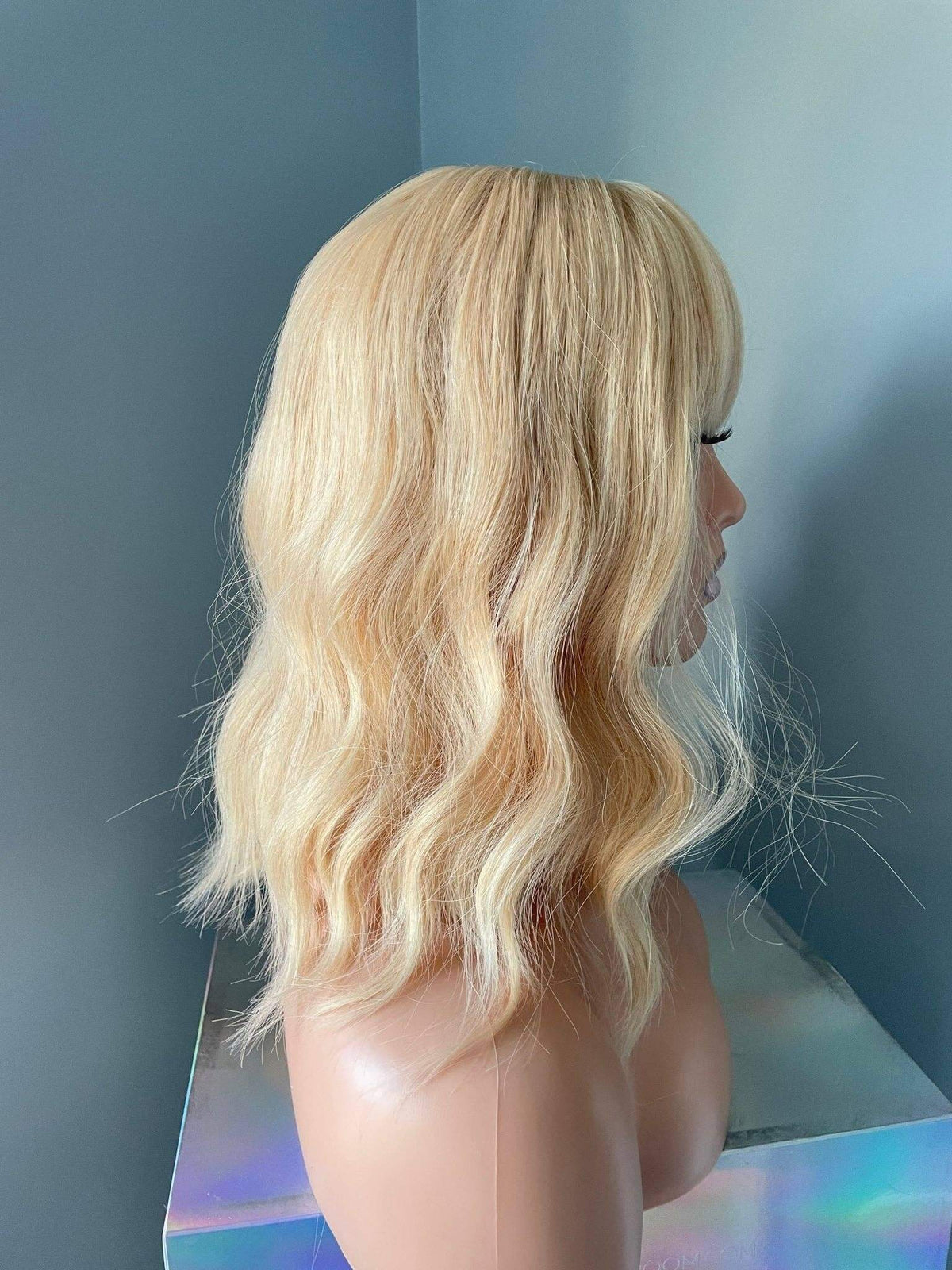 Blonde wig on a mannequin head against a plain background