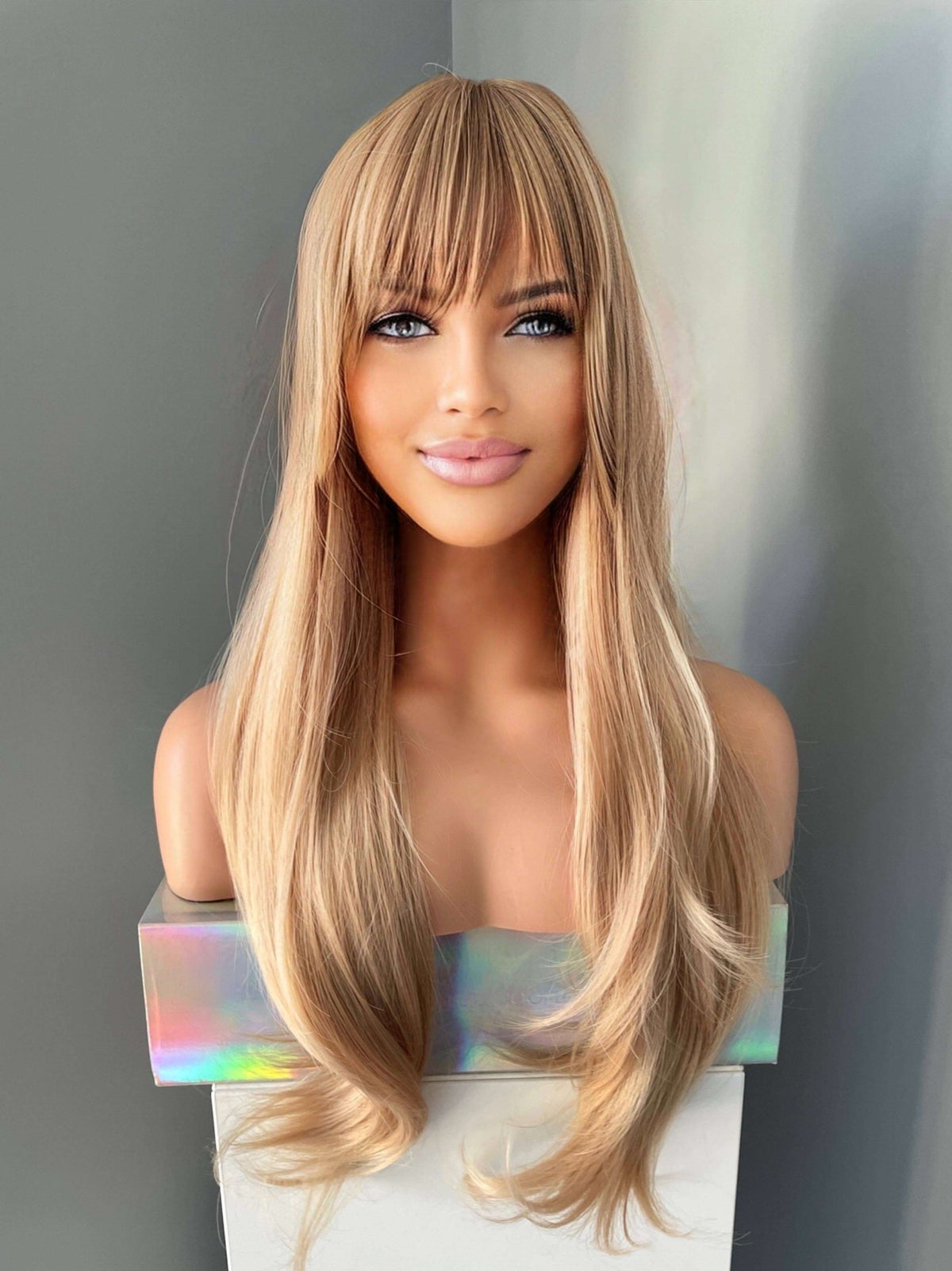 Blonde wig with bangs on a mannequin head against a gray background