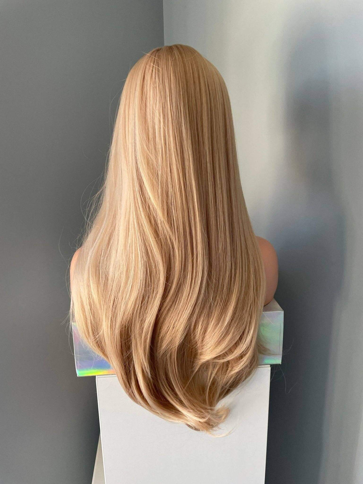Blonde wig on a mannequin head against a plain background