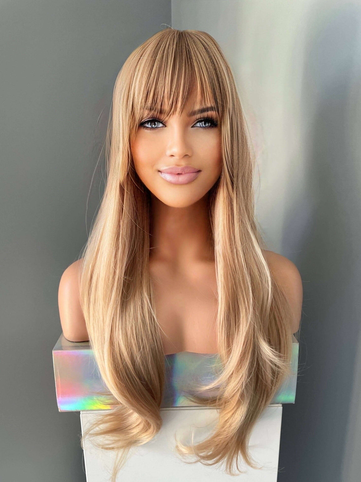 Blonde wig with bangs on a mannequin head against a gray background