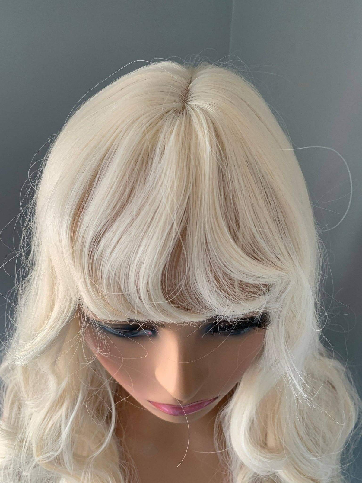 Top view of the Gwen Long Blonde Layered Wig with Bangs showcasing loose waves and curtain bangs.