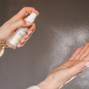 Person using Hand & Surface Spray to sanitize hands with a fine mist for cleanliness and protection.