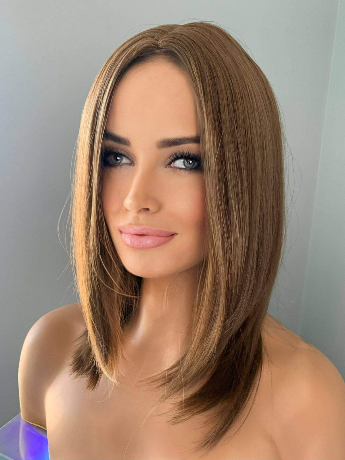 Mannequin head with a brown wig on a gray background