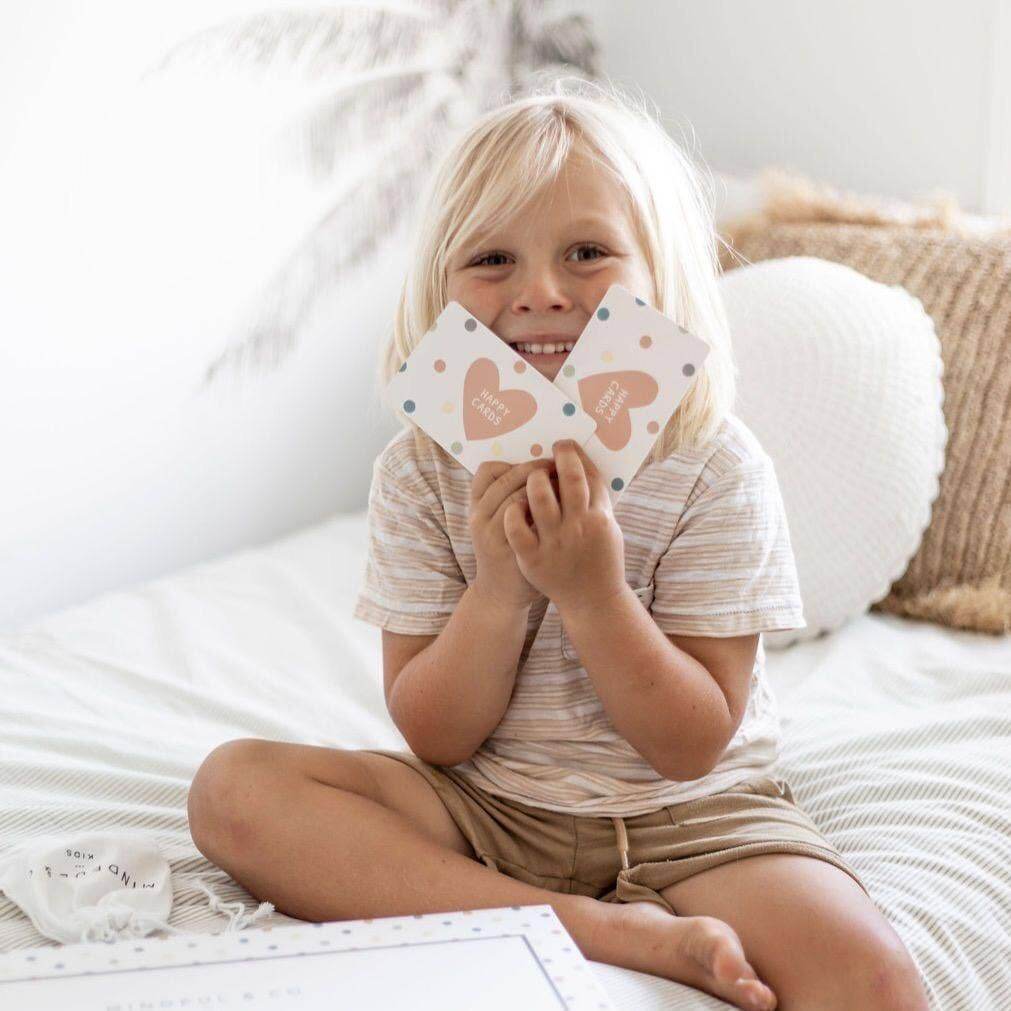 Child holding heart-shaped cards on a bed