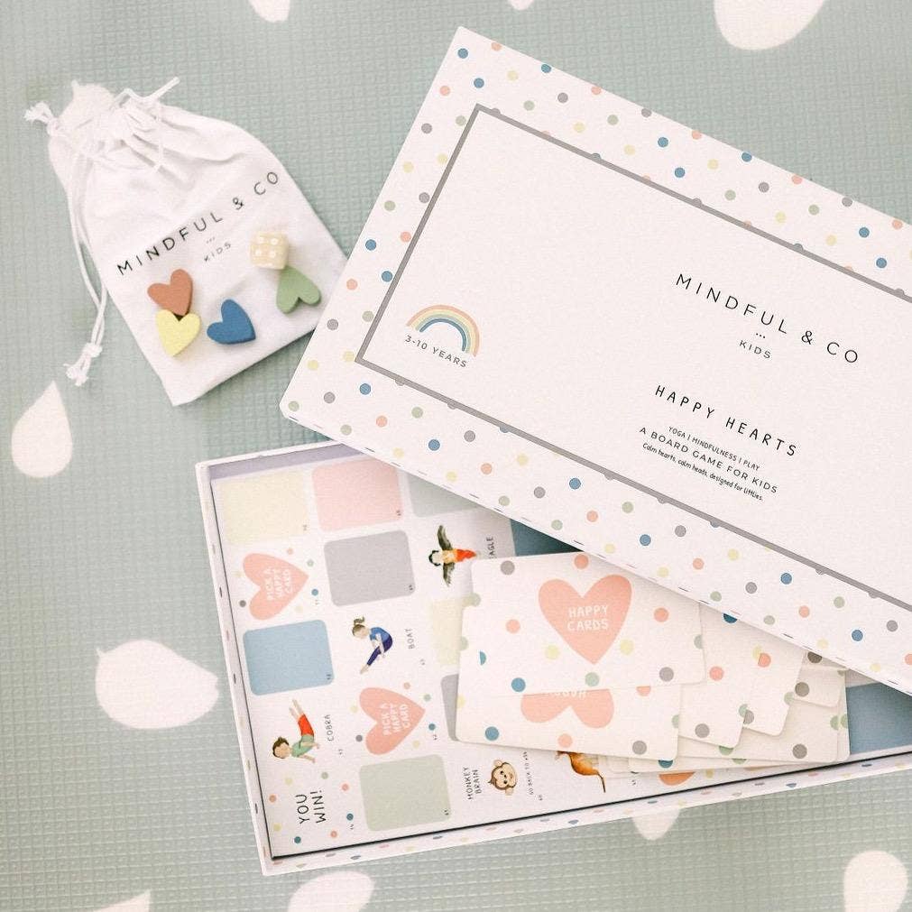 Colorful heart-themed board game and accessories on a light green surface with 'Mindful & Co' branding.