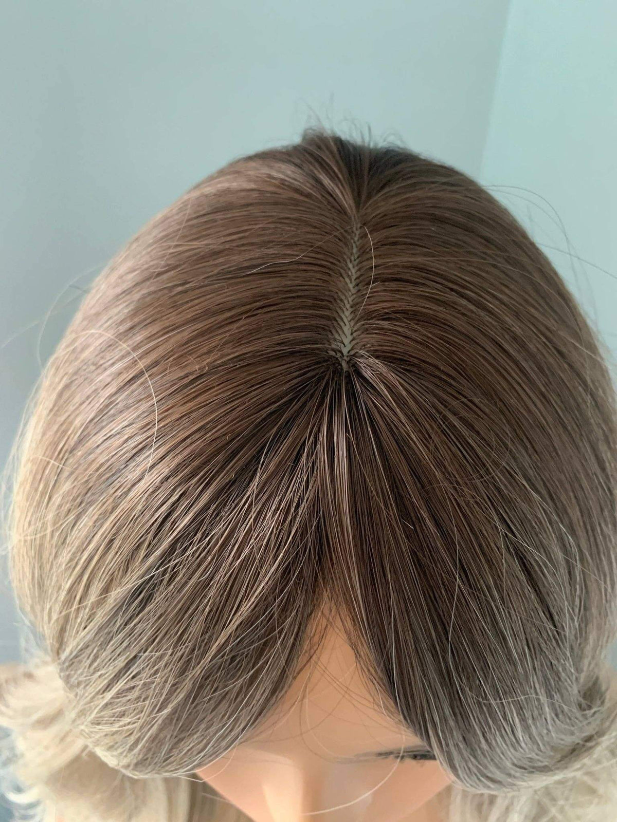 Top view of the Harlow Rooted Ash Light Brown Wig with Bangs, showcasing its soft texture and natural color blend.