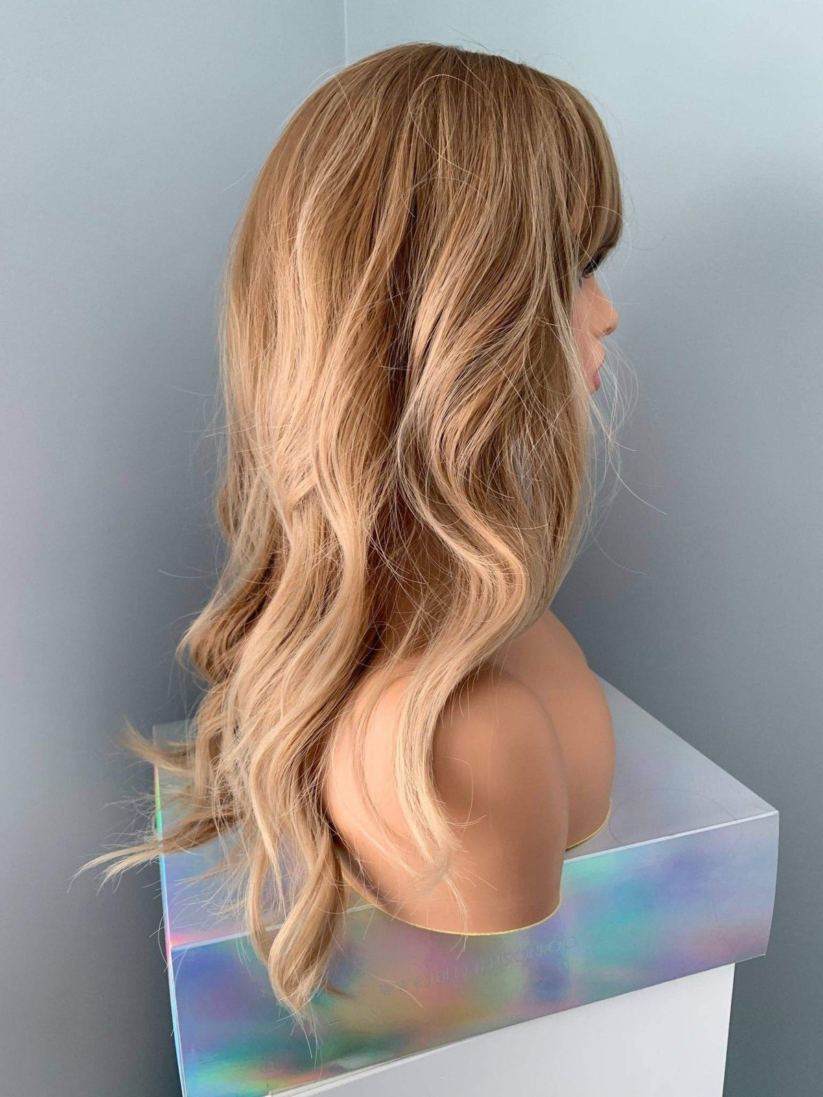 Blonde wig on a mannequin head against a plain background