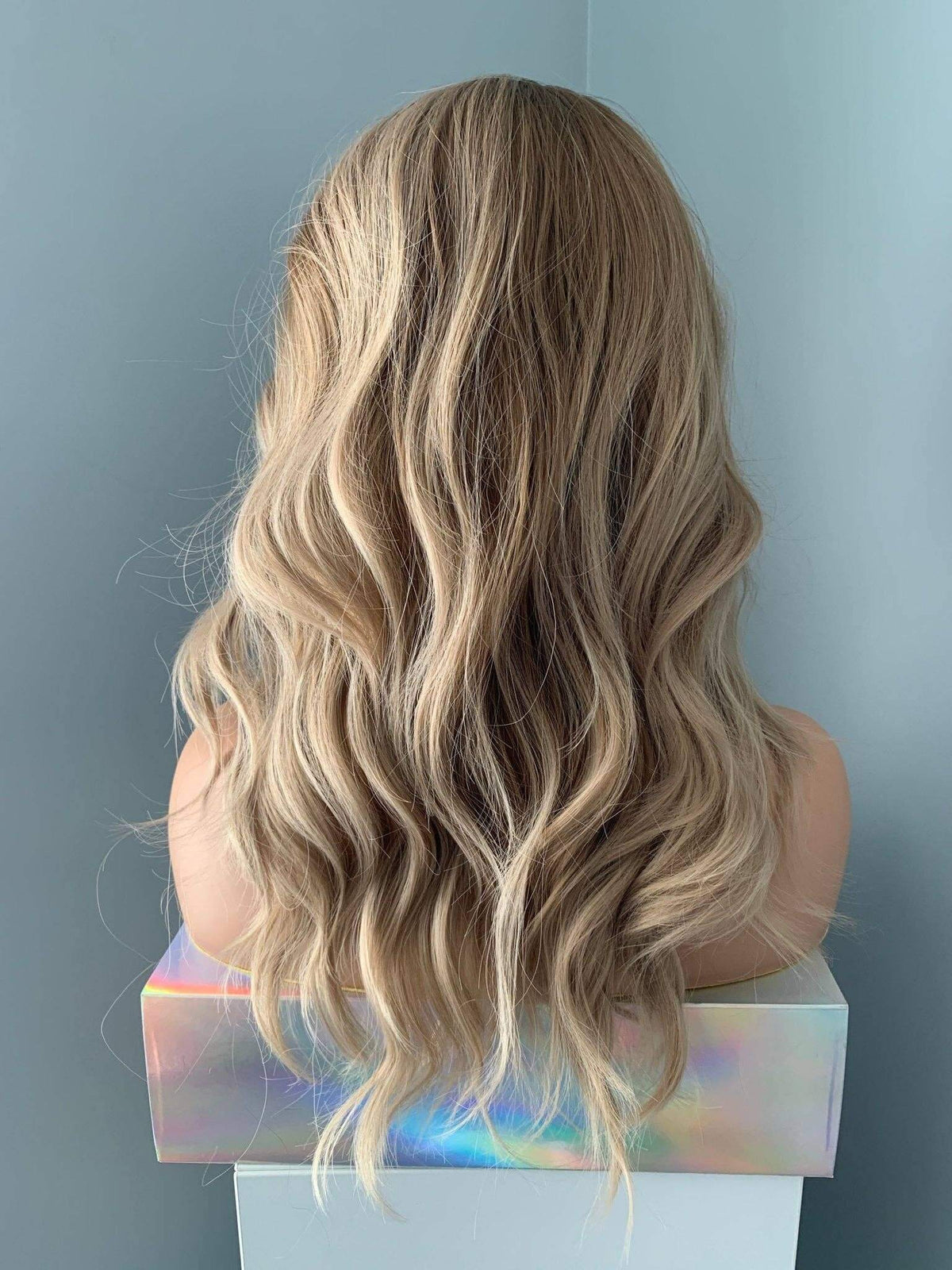 Blonde wig on a mannequin head against a plain background