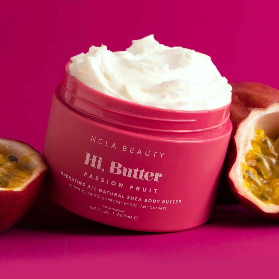 Pink jar of NCLA Beauty Hi, Butter Passion Fruit body butter with passion fruit on a pink background