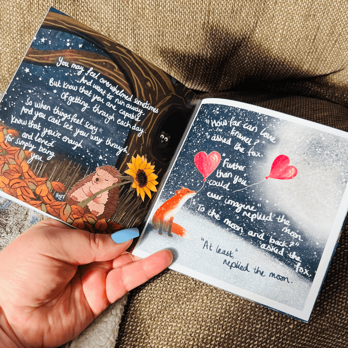 A hand holding the open pages of the Hug In A Book mini book featuring colorful illustrations and uplifting text.
