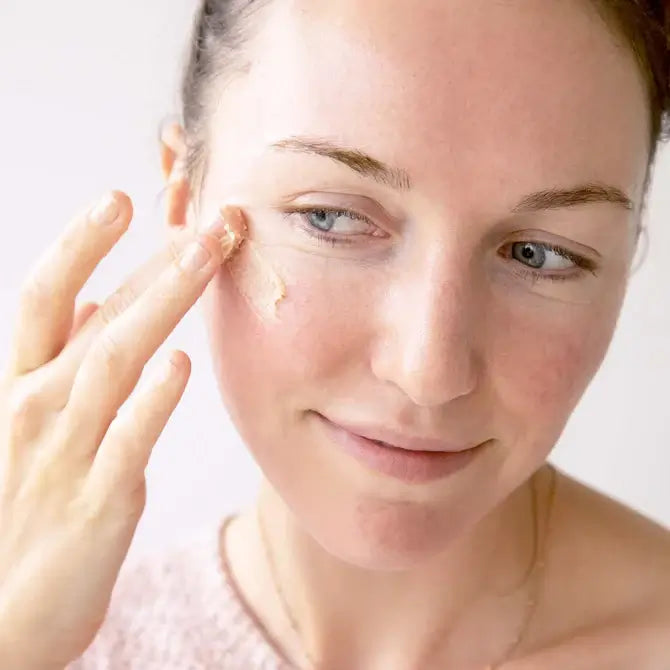 Woman applying Intensive Nourishing Balm to her face for deep moisture and skin nourishment.