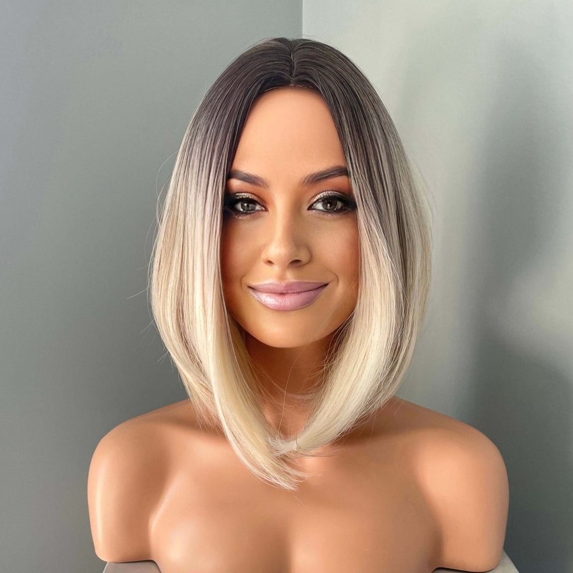 Model showcasing the Katya Short Blonde Rooted Synthetic Bob Wig by The Extension Room, featuring a sleek, stylish look.