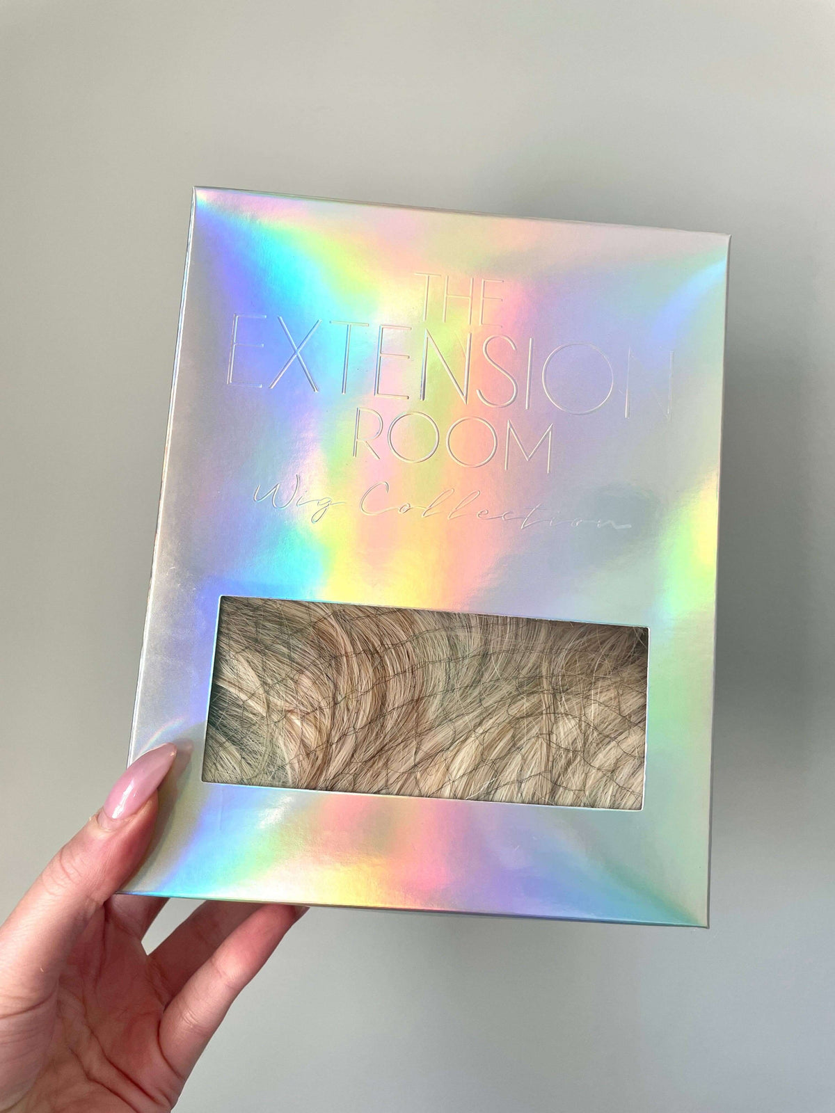 Packaging of The Extension Room Synthetic Bob Wig in a holographic box showcasing the product inside.