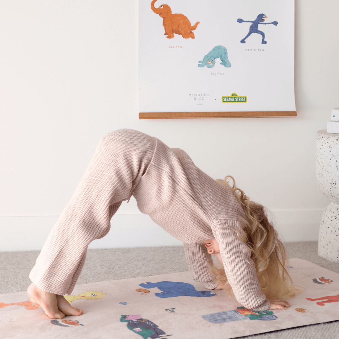 Child practicing yoga pose with Double-sided Sesame Street Yoga Poses Print in the background.