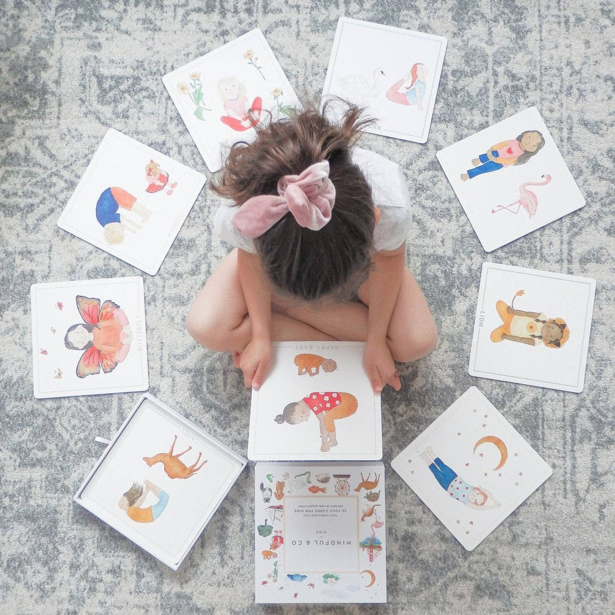Child engaged with colorful Yoga Flash Cards showcasing various yoga poses on the floor.