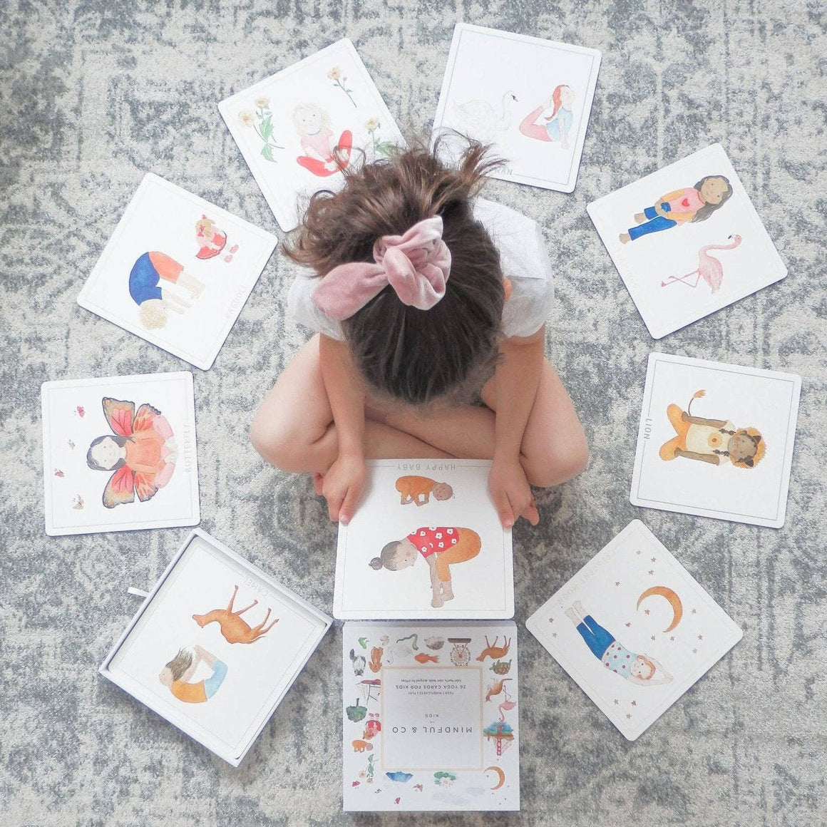 Child engaged with colorful Yoga Flash Cards showcasing various yoga poses on the floor.