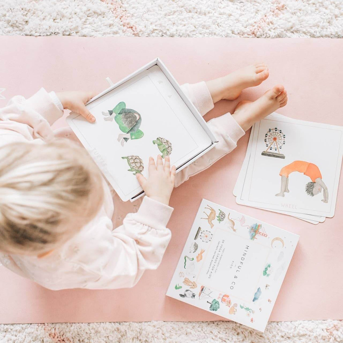 Child engaging with Yoga Flash Cards on a pink yoga mat, promoting mindfulness and movement.