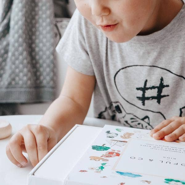 Child excitedly exploring the Kids Yoga Flash Cards box, promoting mindfulness and movement.