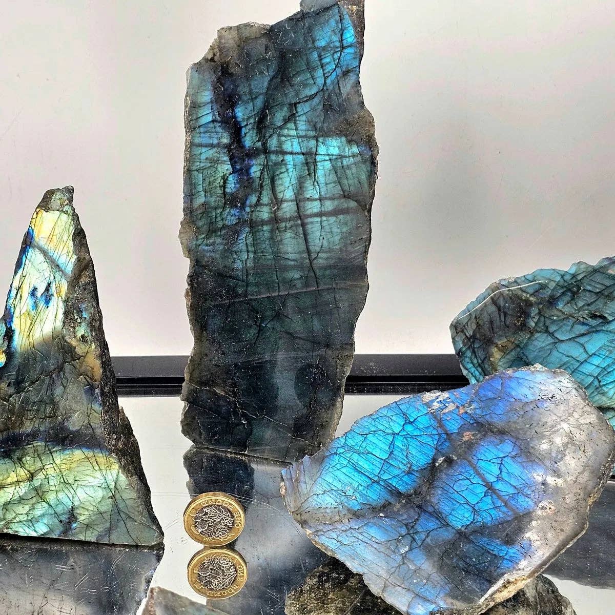 Labradorite crystal with blue and green patterns on a reflective surface