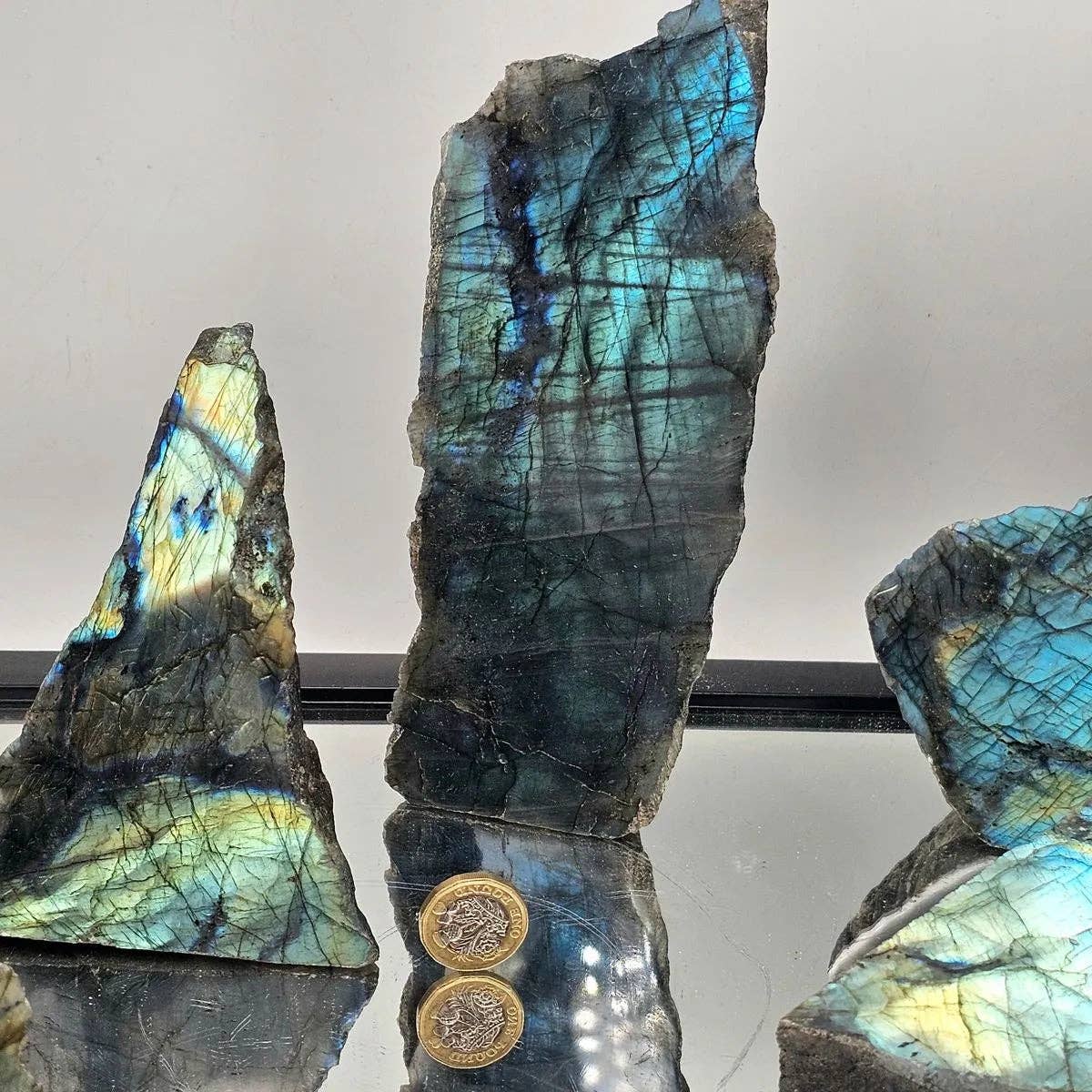 Three labradorite stones with a reflective surface and visible coins underneath.