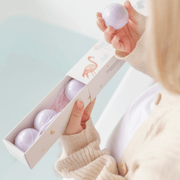 Person holding a pink stress ball with a box of similar balls on a light blue background