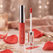 Lip caramel with applicator on a decorative surface with red petals and gold leaves