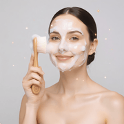 Woman with a facial mask holding a brush against a gray background