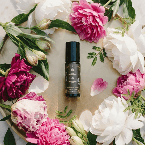 Love - Luxury Essential Oil Blend (10ml) - Annmarie Skin Care bottle surrounded by colorful flowers on a tray.