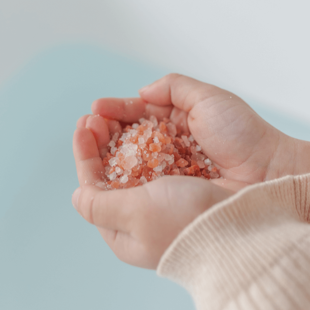 Child's hands holding Magnesium Calming Soak 600g with colorful mineral salts.