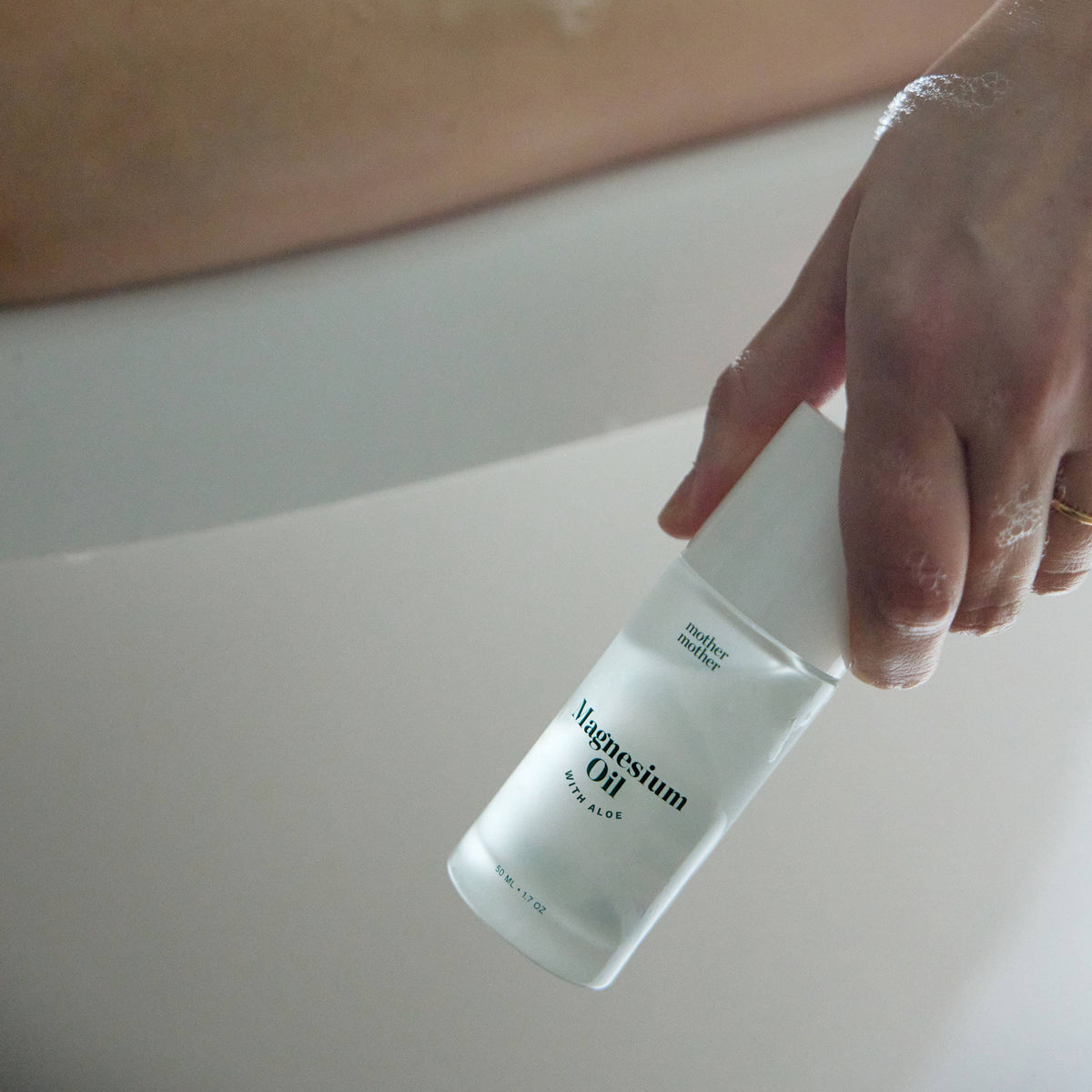 Hand holding Magnesium Oil + Aloe Roller, showcasing targeted magnesium relief in an easy-to-use format.
