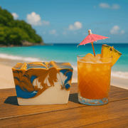 Mai Tai Soap Bar - Soap Boutique next to a tropical cocktail on a beach table with ocean in the background.