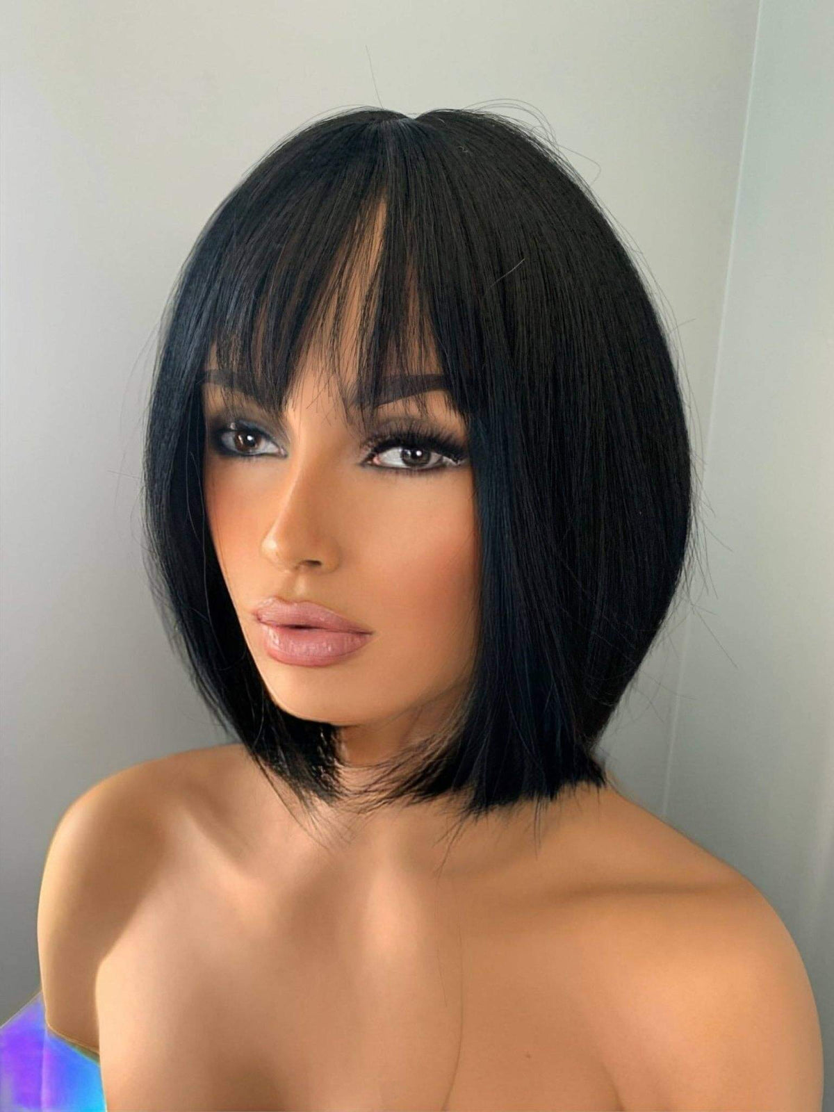 Person with a black bob haircut and bangs against a plain background